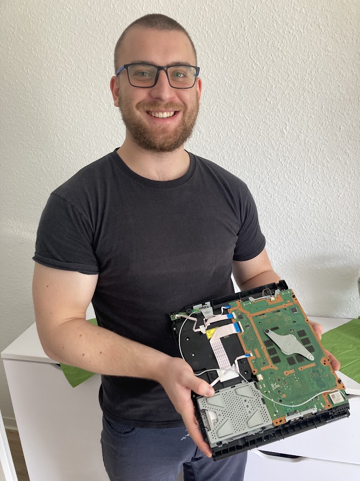 Paul hält ein geöffnetes Gerät mit sichtbarer Platine in den Händen