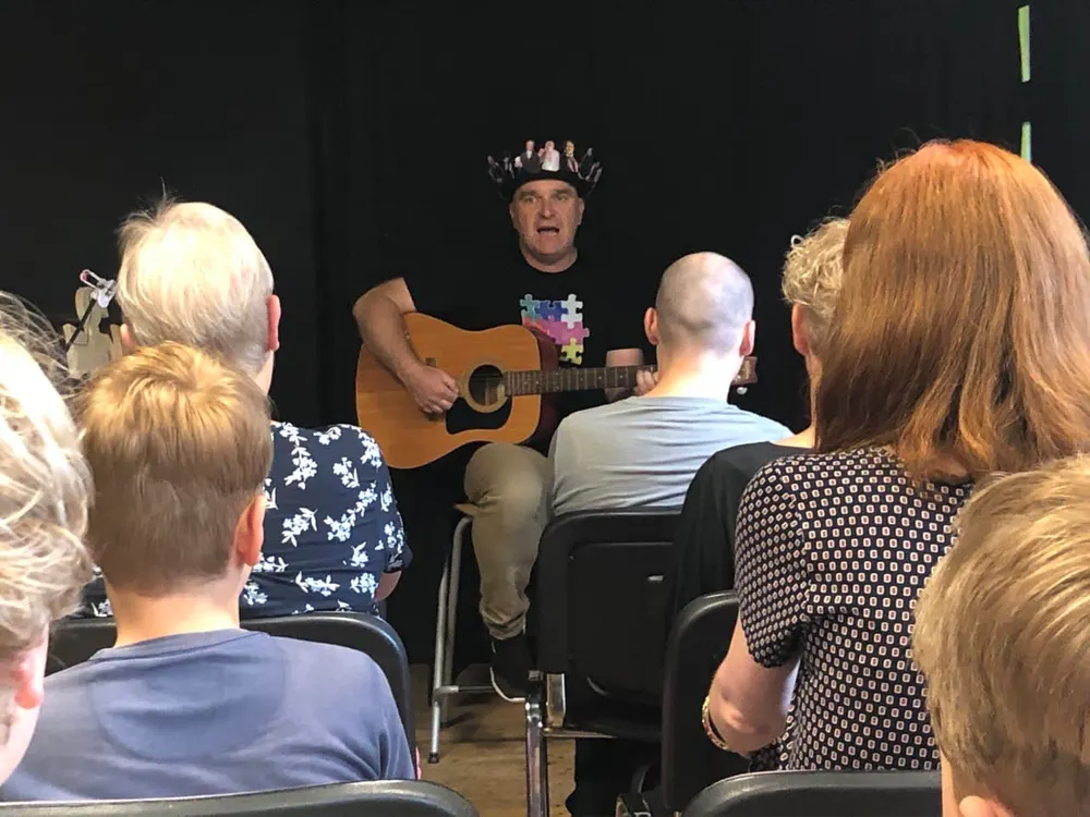 Musiker mit Gitarre singt für die dicht davor sitzenden Gäste