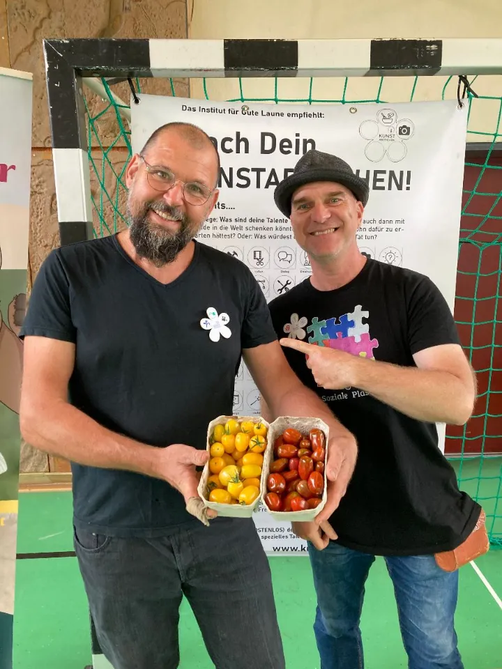 Zwei Träger mit Kunstabzeichen und selbst geernteten Tomaten
