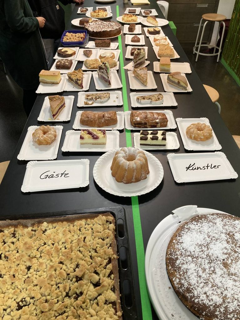 Der lange Kuchentisch beim Kuchenkonzert mit den Schildern „Gäste“ und „Künstler“